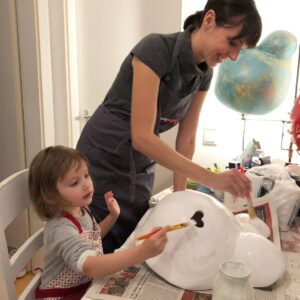 Eine Frau und ihr Kind bemalen den Gipsabdruck einen Babybauchs.