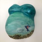 Ein Gipsabdruck eines Babybauches mit Brust und Bauch, gestaltet in den Farben des Meeres mit Kieselsteinen, dem Landesumriss von Kroatien und dem Namen und Geburtsdatum des Babys.