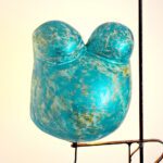 Ein 3D-Abdruck eines Babybauches aus Gips von Brust und Bauch, gestaltet in den Farben Türkis und Grün auf einem Gestell.