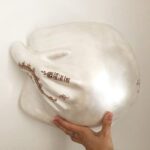 Ein Gipsabdruck eines Babybauches mit einer Hand die den Bauch umfasst, gestaltet mit Henna-Tattoos und in der Farbe Perlmutt.