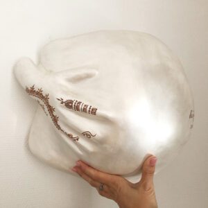 Ein Gipsabdruck eines Babybauches mit einer Hand die den Bauch umfasst, gestaltet mit Henna-Tattoos und in der Farbe Perlmutt.